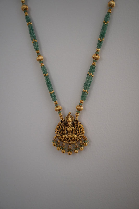A gold, green, and pink necklace with a floral motif and bead details, accompanied by matching earrings.